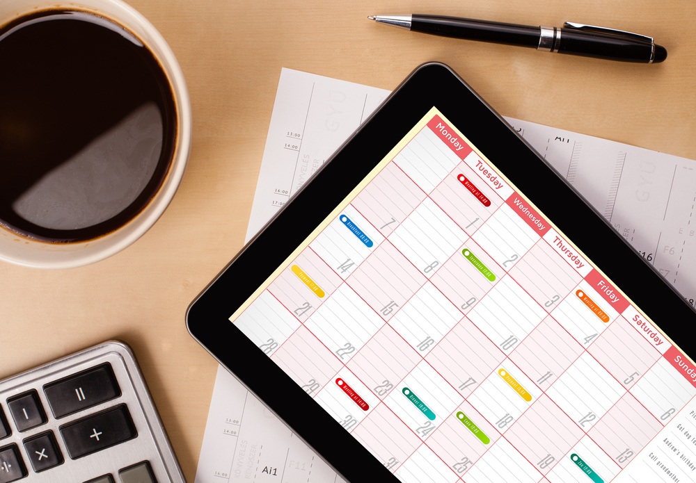 Workplace with tablet pc showing calendar and a cup of coffee on a wooden work table close-up-1